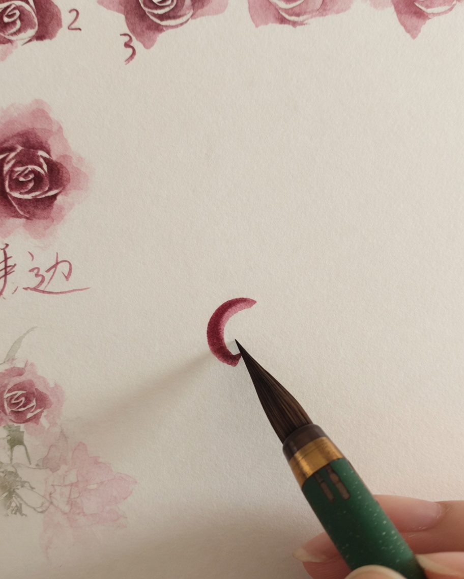 A watercolor brush adding small, thin pink strokes around the previously painted rose center.