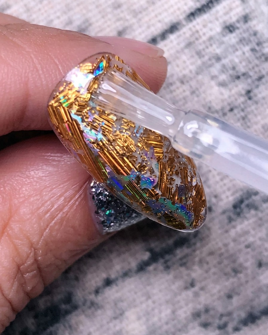 A layer of clear strengthening gel being applied over the foil design.