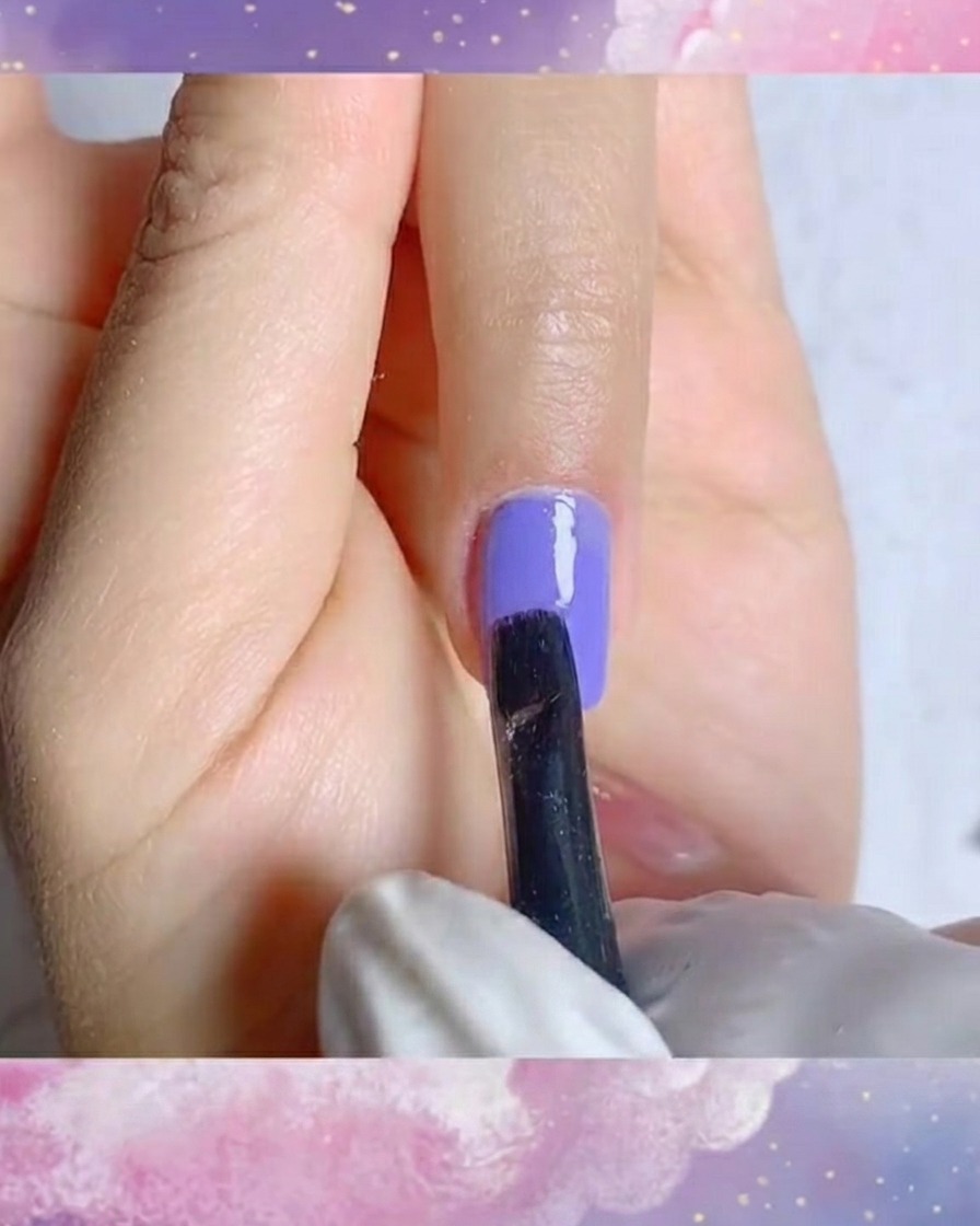 A close-up shot of a fine liner brush creating precise white petal strokes on a purple gel base.