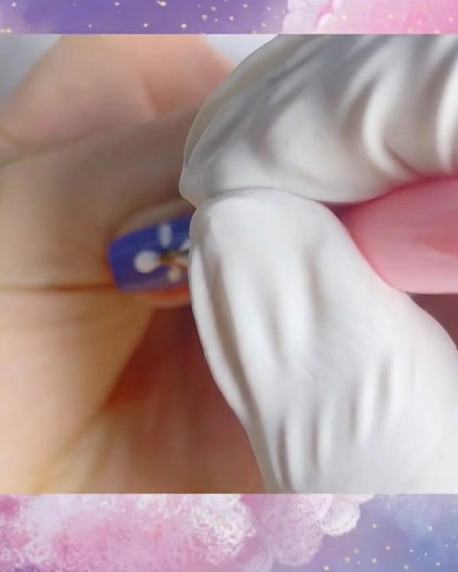 A close-up of a finished white daisy design on a purple nail base, created with thin, clean strokes.