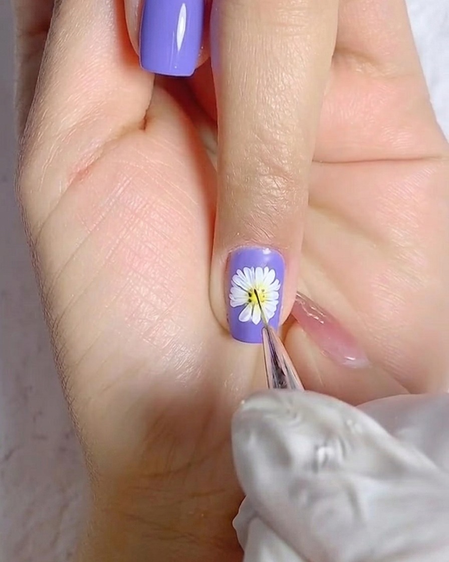 A brush applying a smooth coat of white gel polish to a thumb nail.