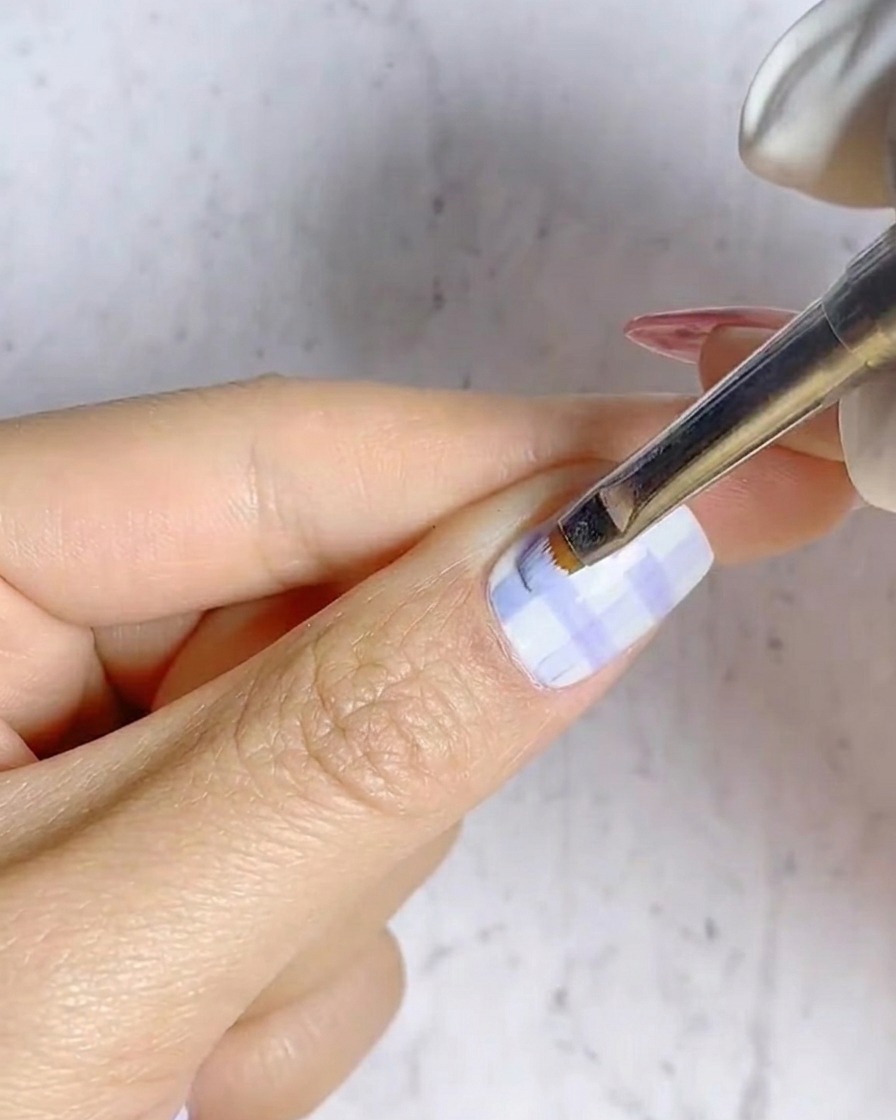 A liner brush drawing horizontal blue lines over existing vertical lines to form a grid.