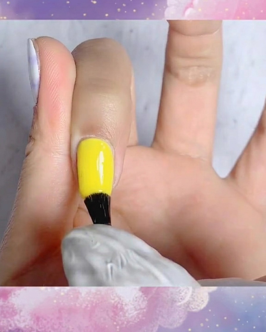 A brush applying matte top coat onto a fingernail with a hand-painted blue and white plaid design.