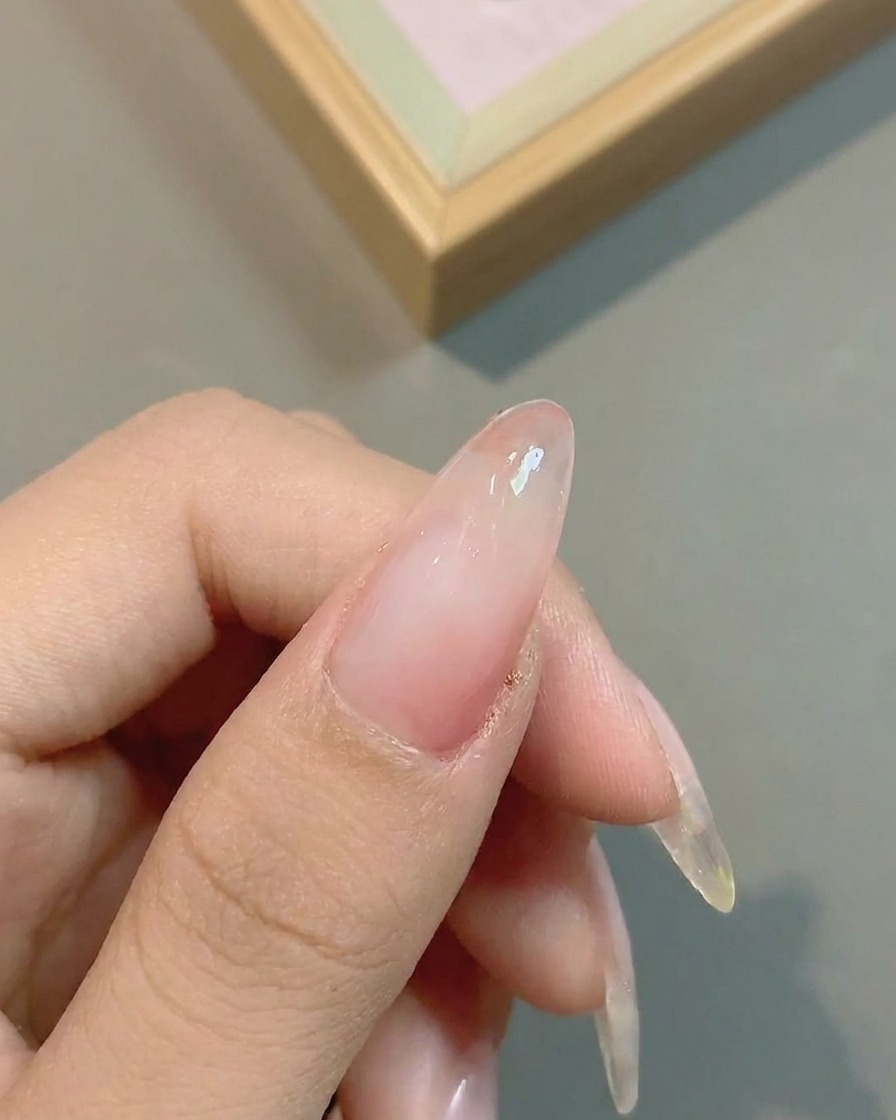 The nail surface appearing with a more saturated pink gradient after the second layer of color is applied.