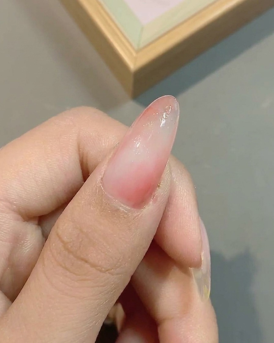 Nail surface showing the application of cloud-effect glitter over the existing pink gradient.