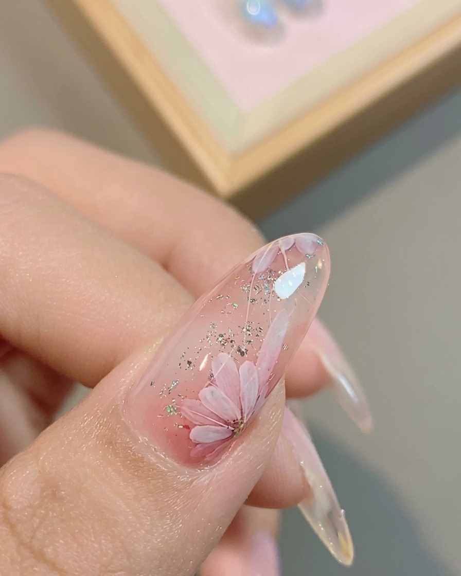 A brush applying a final glossy top coat over the completed daisy design.