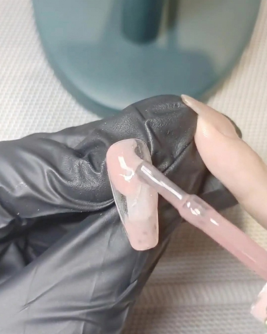 A nail tip resting inside a UV lamp, mid-curing process.