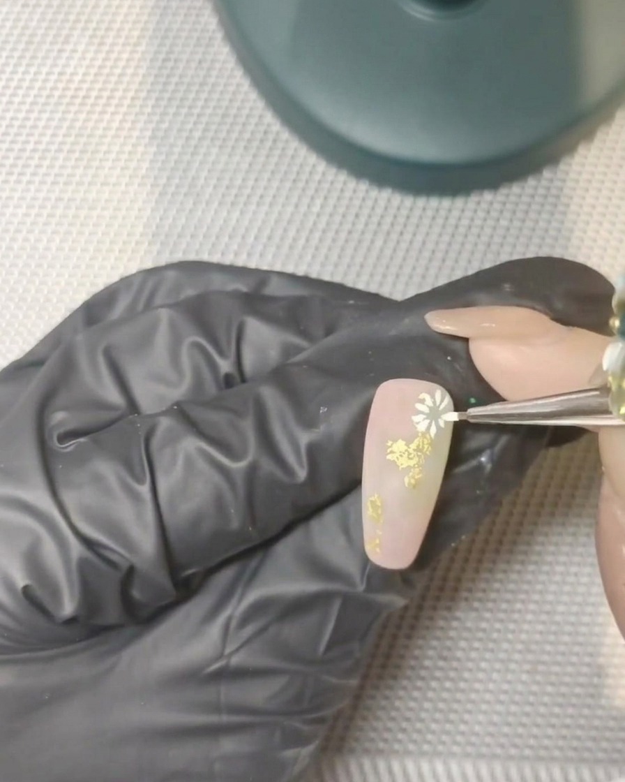 A hand with decorated nails placed inside a professional UV lamp for curing.