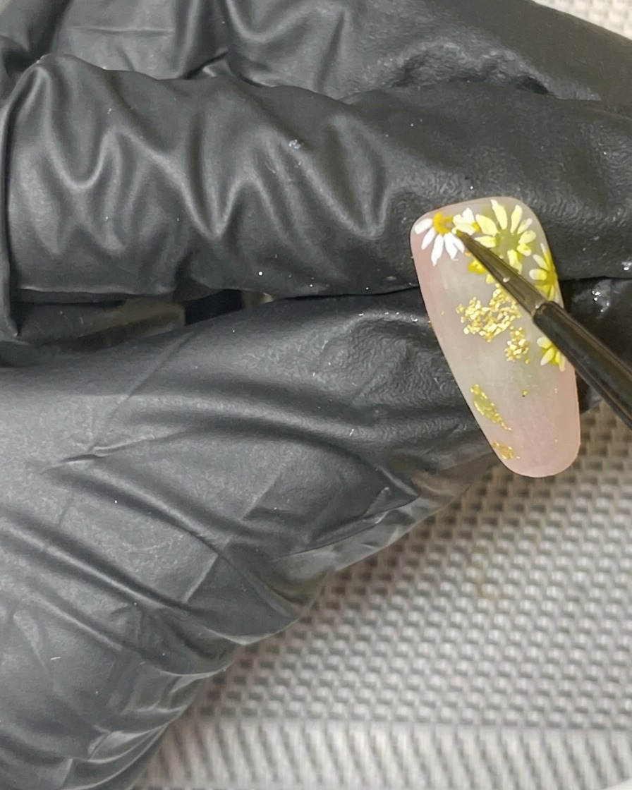 A close-up view of the finished daisy nail art design curing inside a lamp.