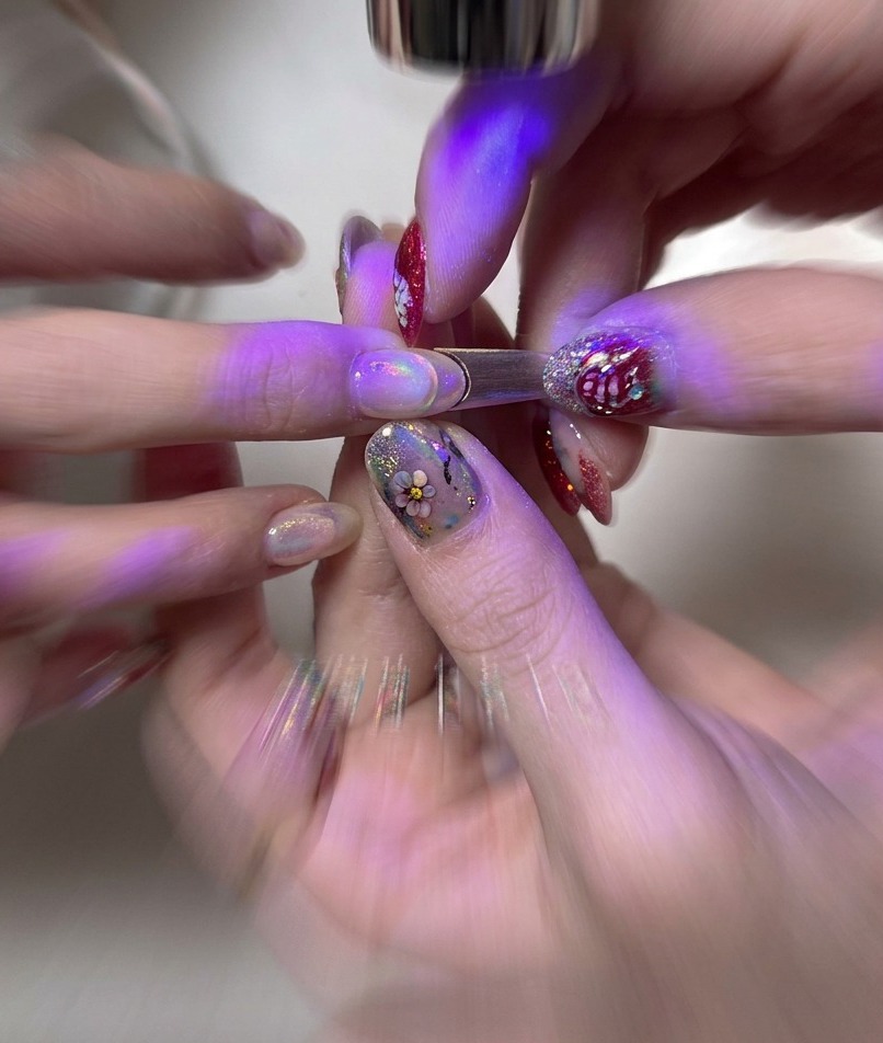 A finger placed under a small, portable UV/LED lamp curing the gel base layer.