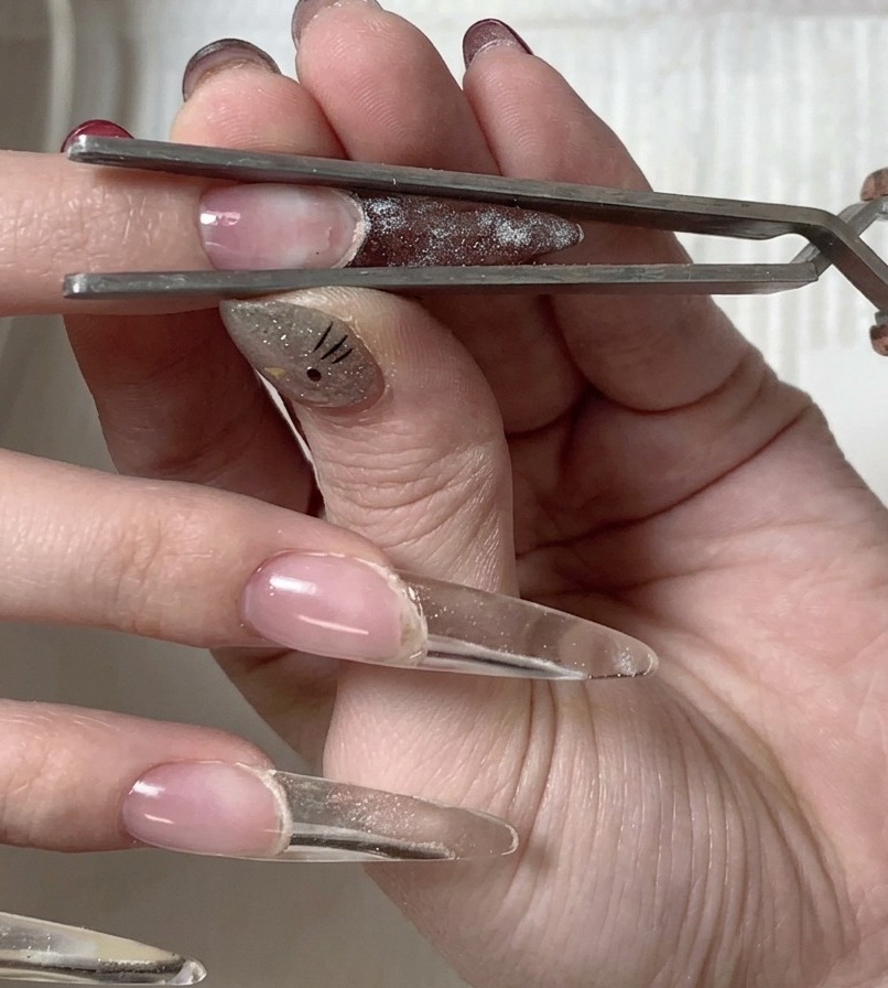 A hand positioned to expose the underside of the nail tip to the UV/LED lamp for a final cure.