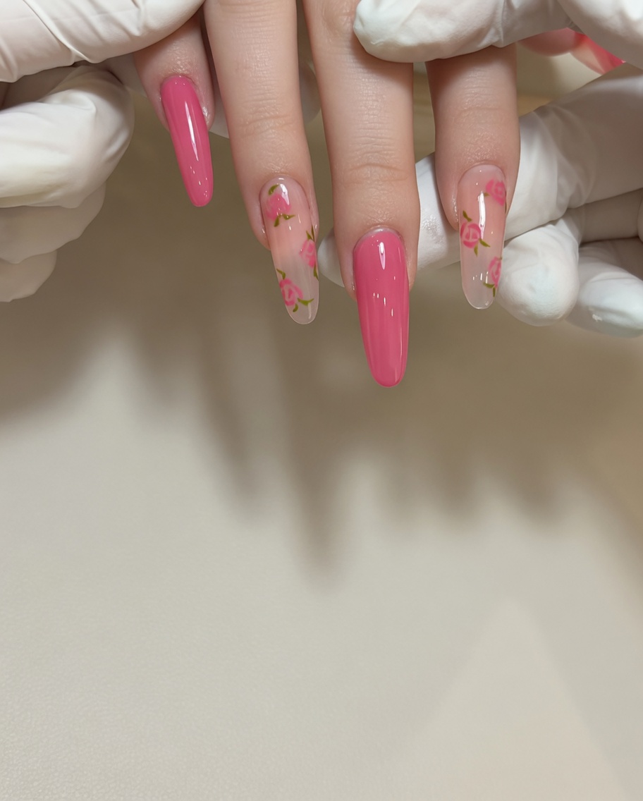 A close-up of a fine-detail brush applying red gel polish to create a small rose petal on a natural-toned nail.