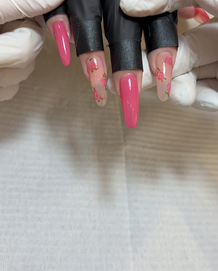 A close-up of a brush applying deeper red gel to the middle of the second rose cluster on the nail.