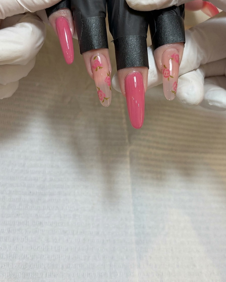 A close-up of the fine-detail brush painting a third rose petal cluster near the tip of the nail.