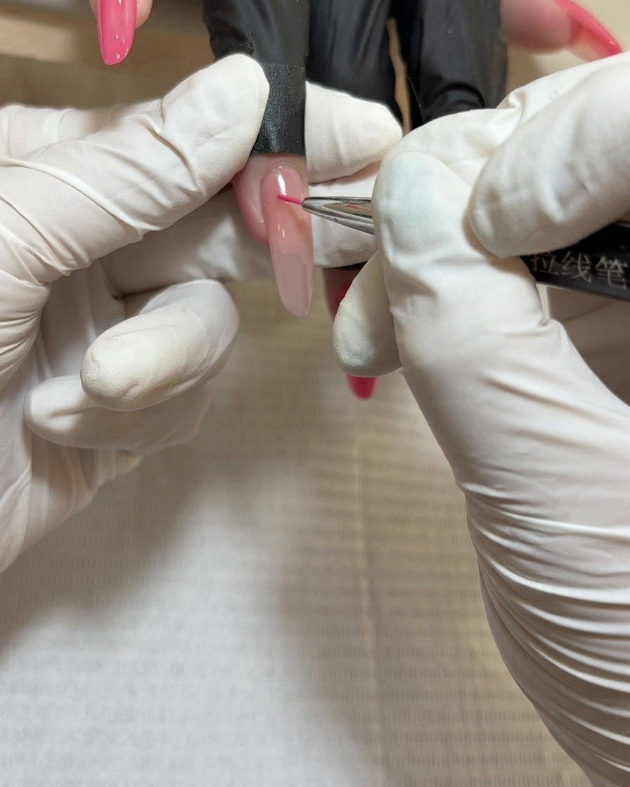 A close-up of a liner brush applying deep red gel to the center of the third rose petal cluster.