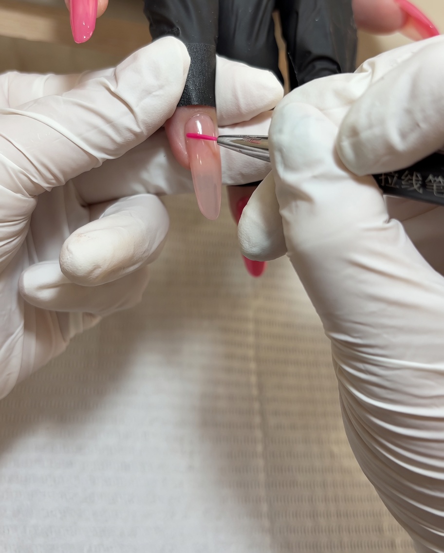 A brush applying a final glossy top coat over a nail decorated with hand-painted roses.