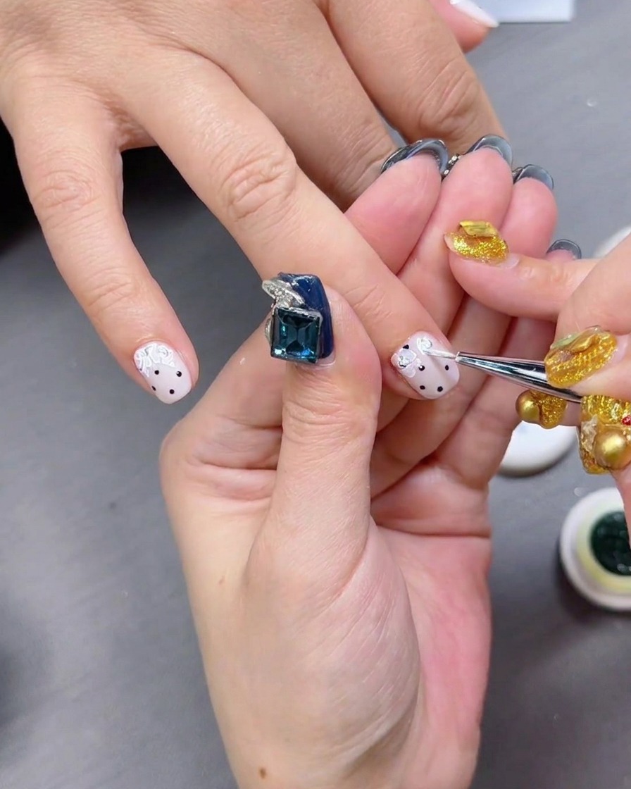 A glossy top coat being applied over nails with black polka dots.