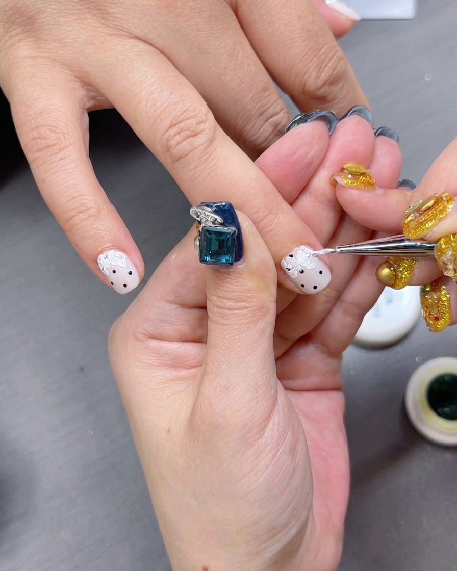 A fine brush applying creamy white oil-painting gel to create petal shapes.