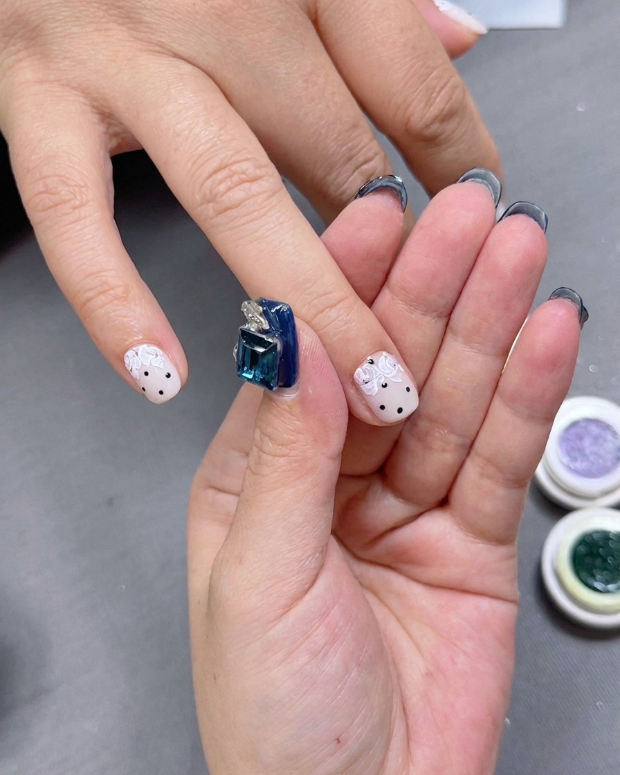 A nail artist applying small green gel accents around the rose petals.