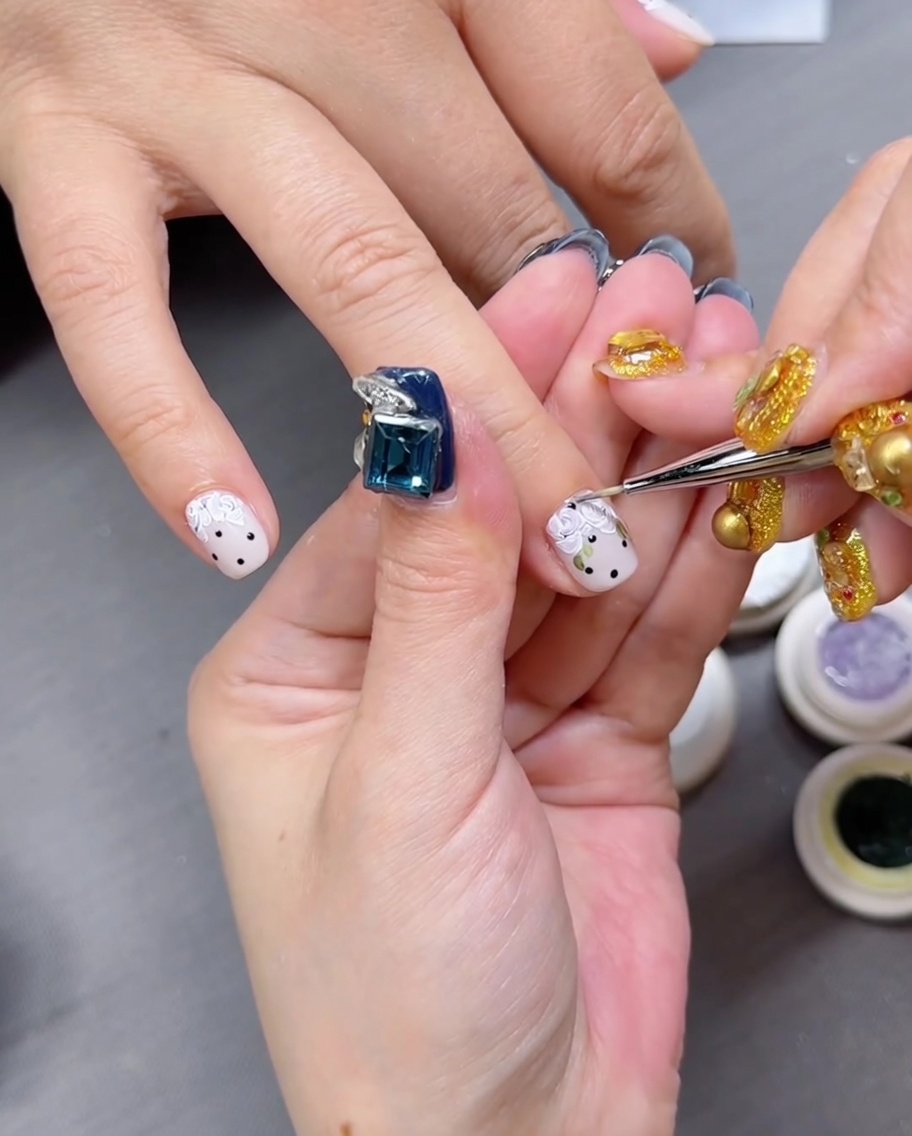 A close-up view of a hand with floral-painted nails resting inside a professional LED nail curing lamp.