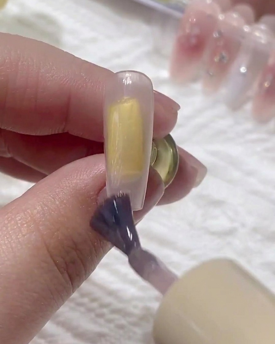 A brush applying a second layer of base gel over the previous layer on the nail.