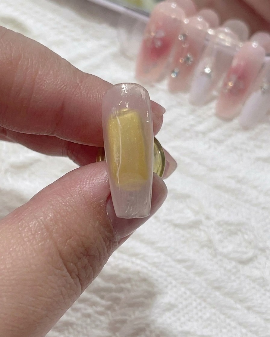 A brush applying clear blooming gel over the nail surface.