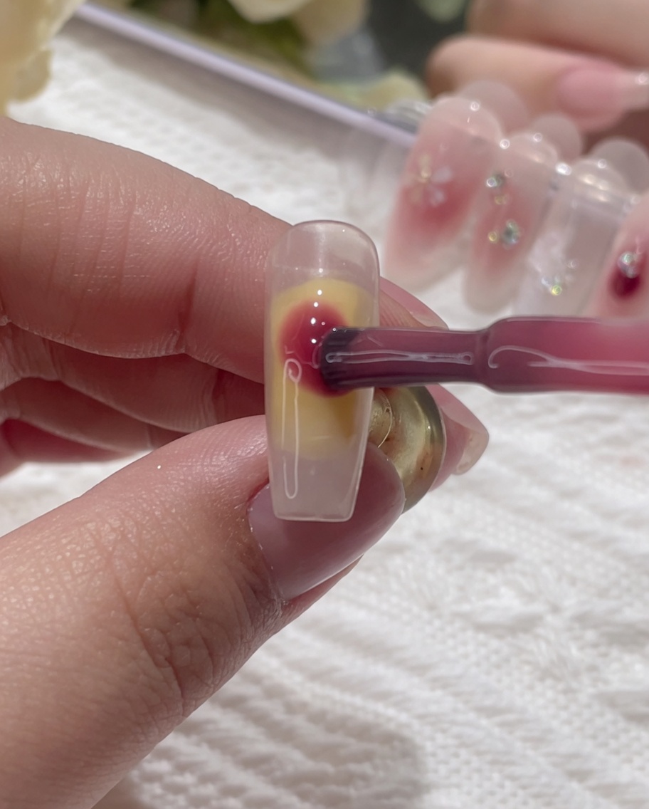 Pink gel being dotted onto the wet surface of the nail.