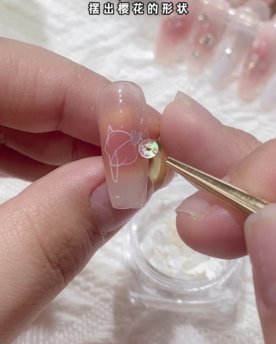 Close-up of tweezers holding a delicate white cherry blossom sequin and placing it onto a nail surface.