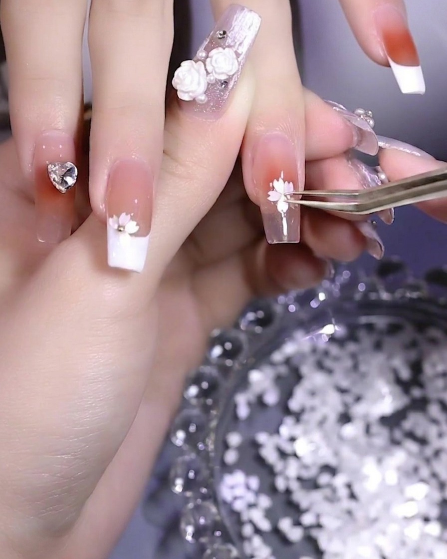 A small metallic bead being placed in the center of a cherry blossom sequin design.