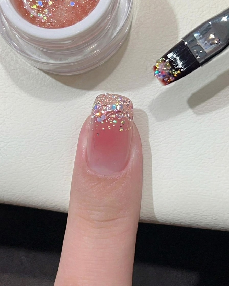 A small dot of vibrant pink gel polish placed in the middle of a nude-coated nail.
