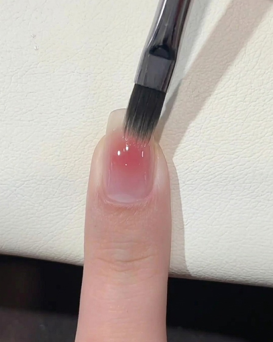 A hand placed under a professional UV nail lamp for curing.