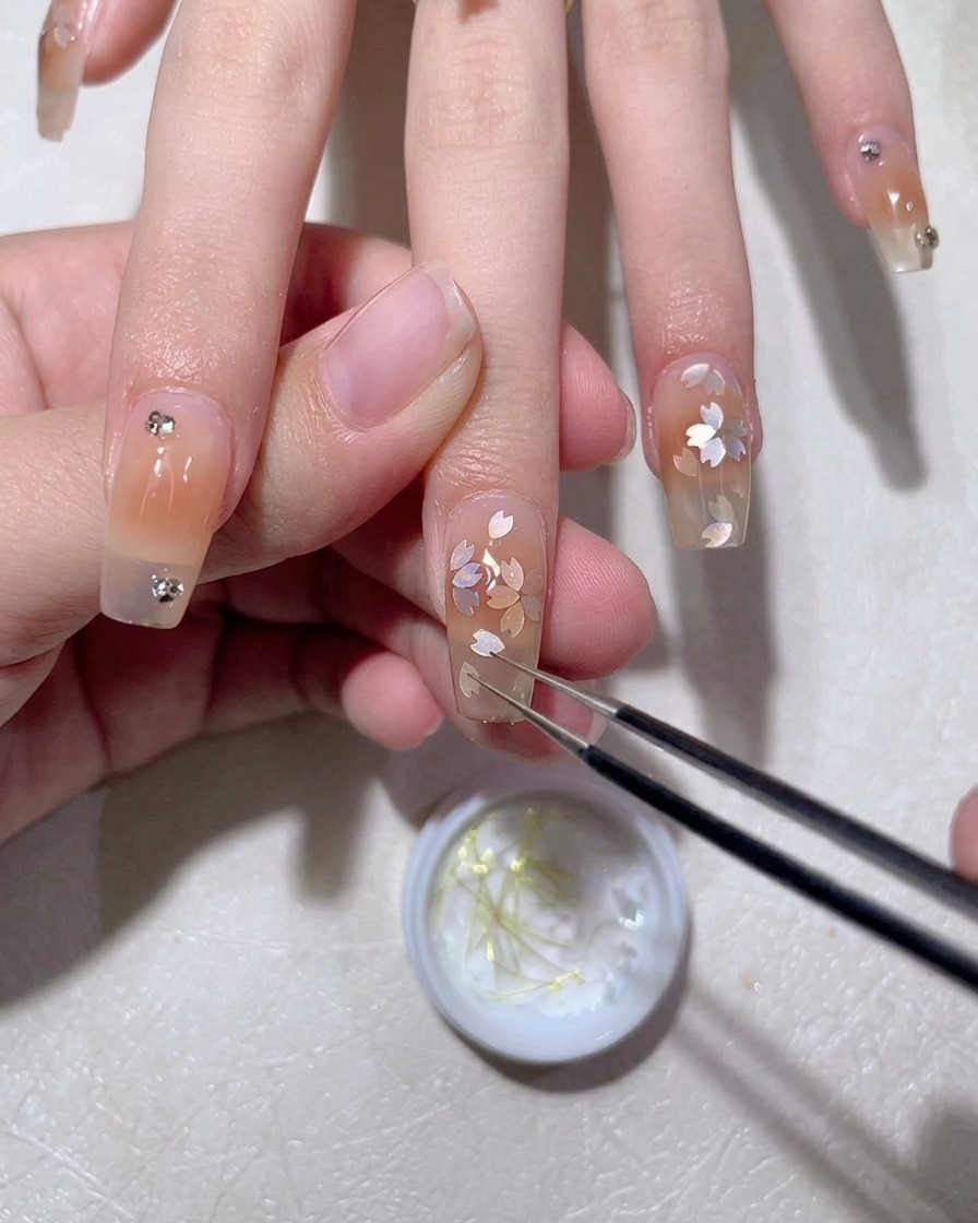 A gel brush applying a smooth layer of top coat over a finished nail design.