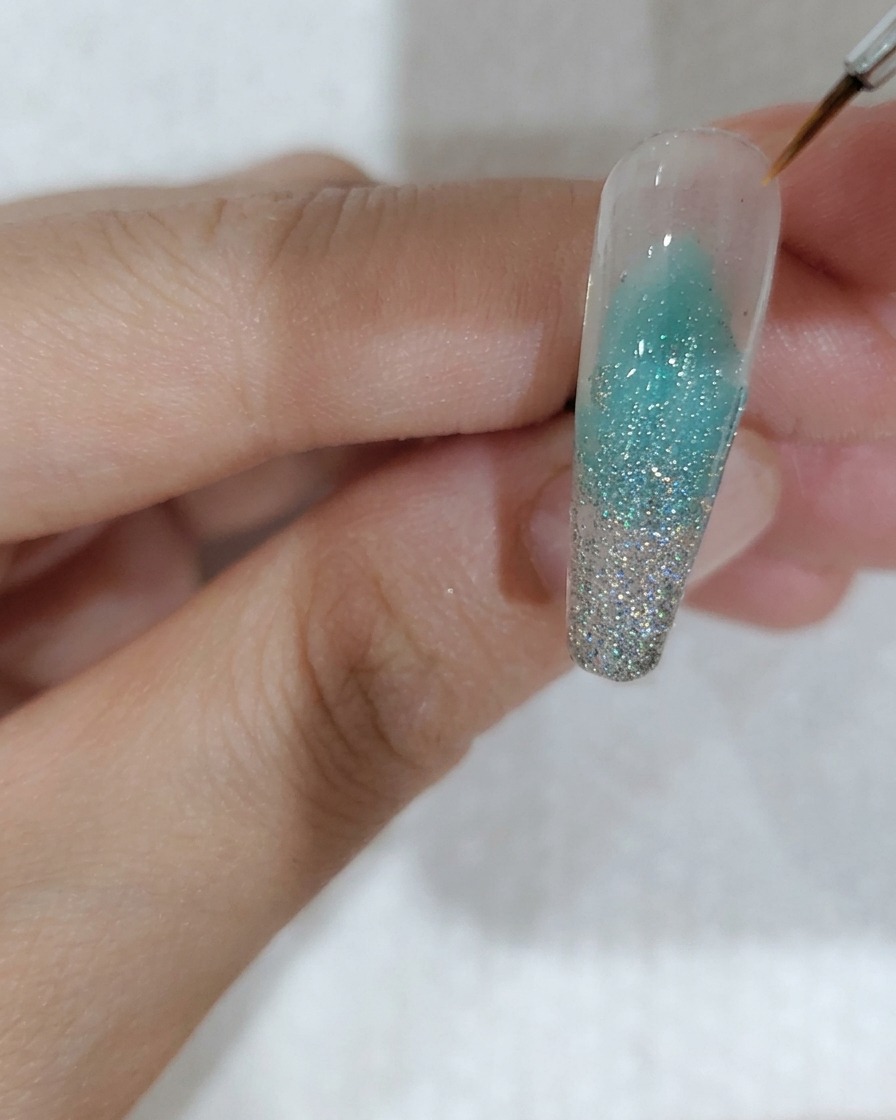 Tweezers placing a single cherry blossom-shaped sequin onto the nail surface.