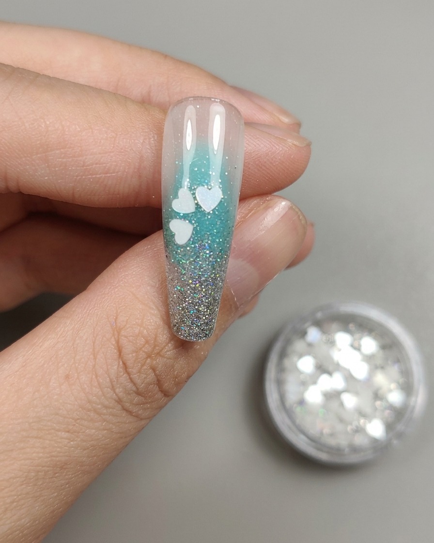 Tweezers placing a second cherry blossom sequin next to the first one on the nail.