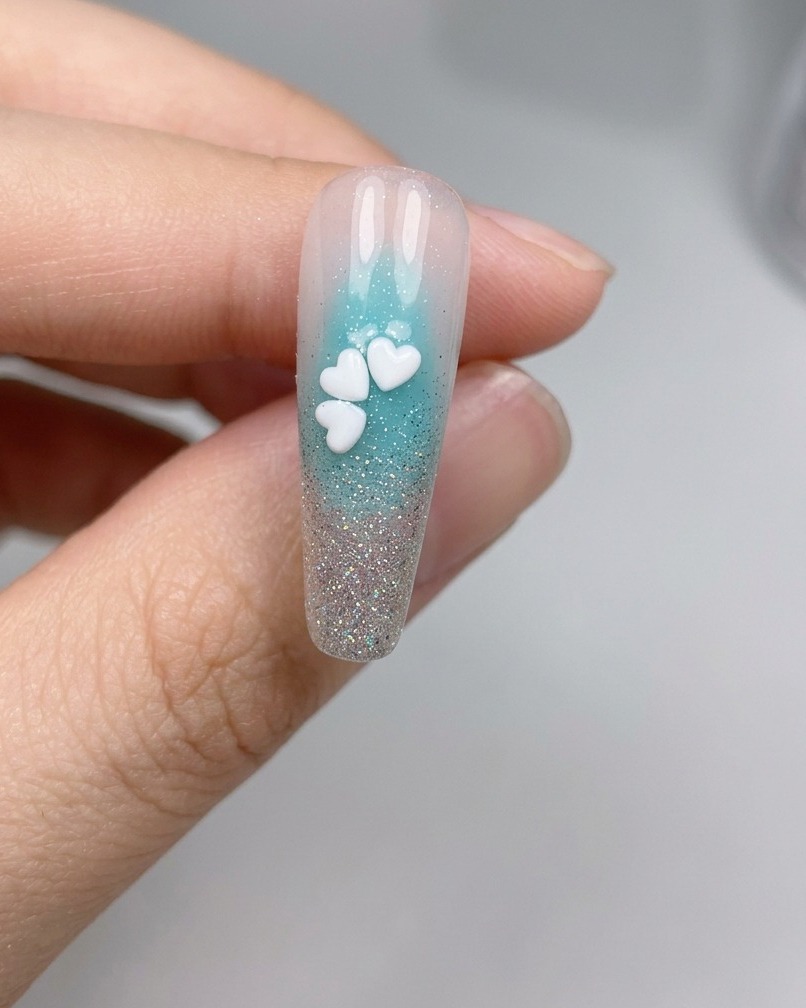 A close-up view of a nail with five white cherry blossom sequins arranged into a complete flower.