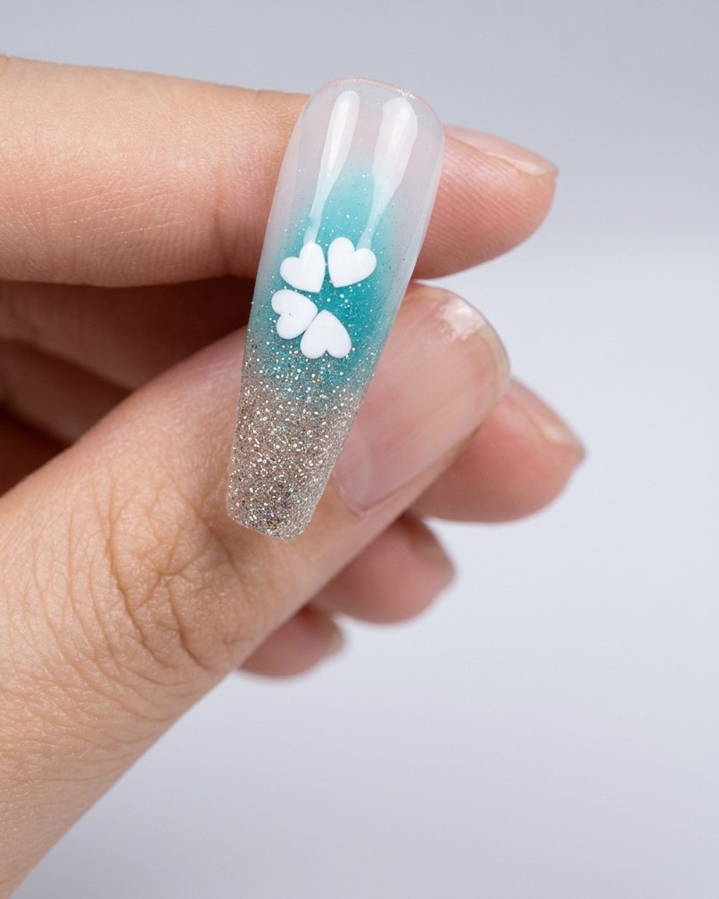 A close-up view of a nail with a tiny dot of glue placed in the center of the white sequin flower.