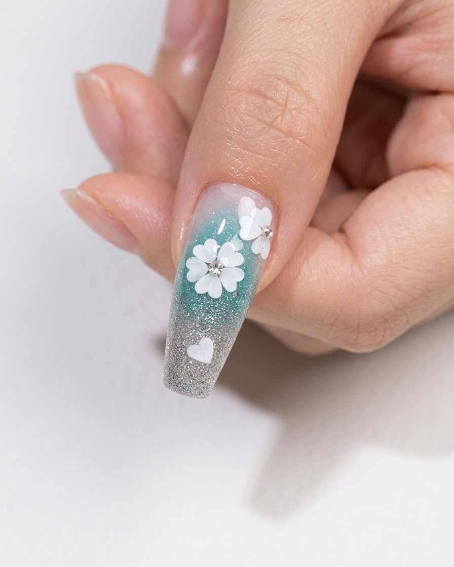A nail art brush applying a layer of clear, glossy top coat over a floral nail design with embedded crystals.