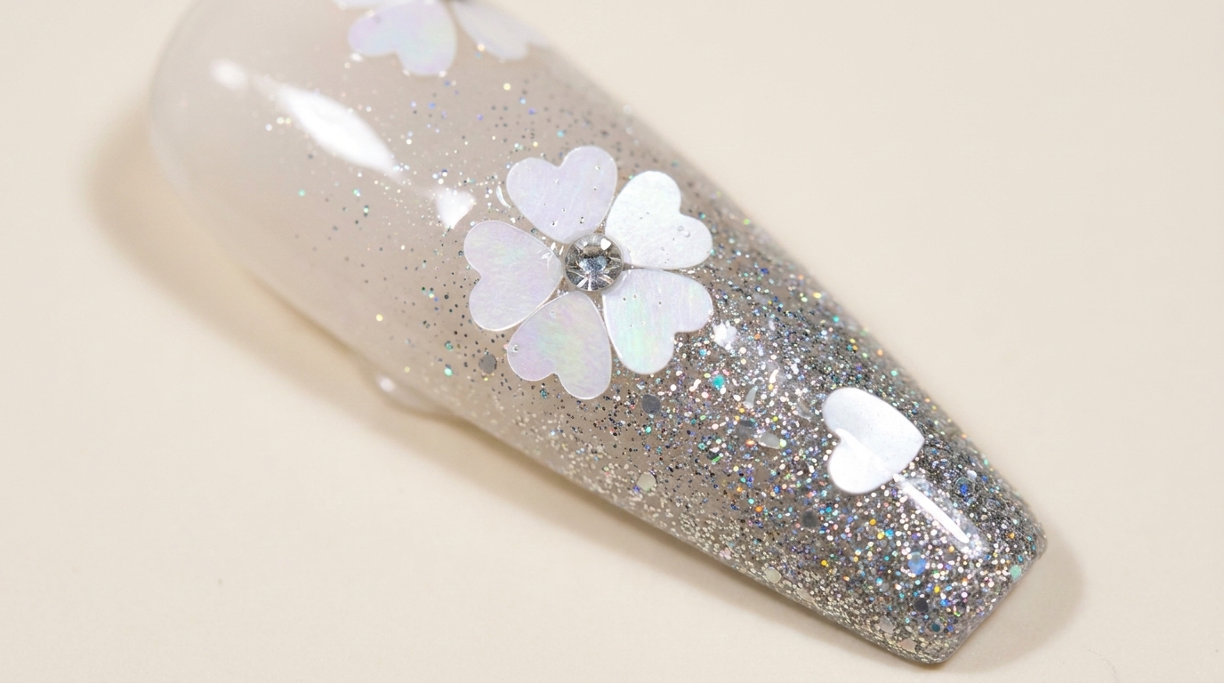A stunning cherry blossom glitter gradient nail design featuring silver sparkle, delicate floral sequins, and a crystal center.