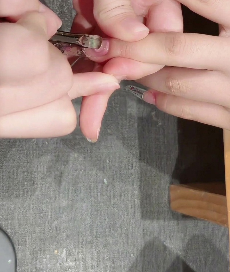 A layer of thick construction gel being smoothed over the nail with an application brush.