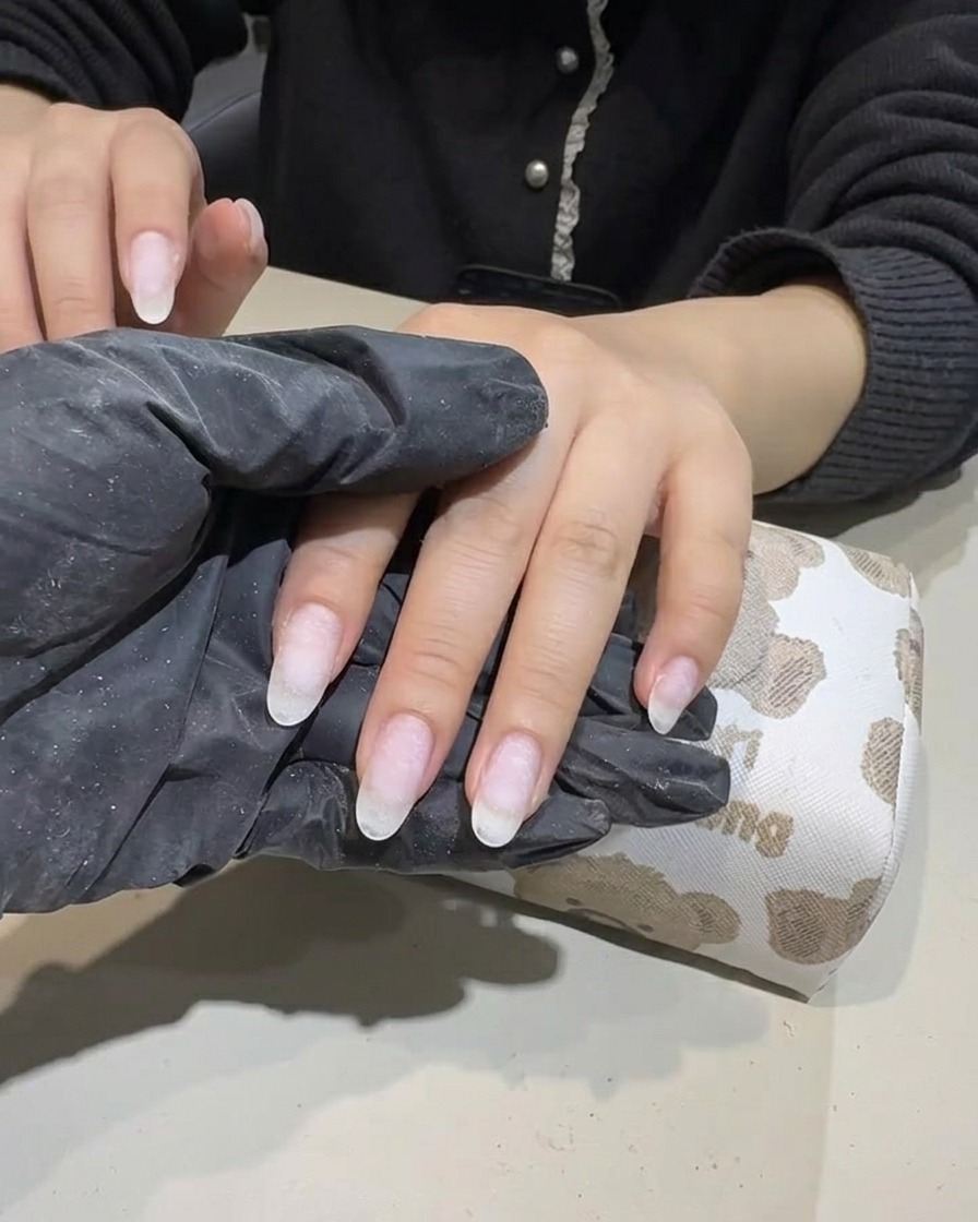 A hand being filed with a nail file to ensure the edges are smooth and properly shaped.