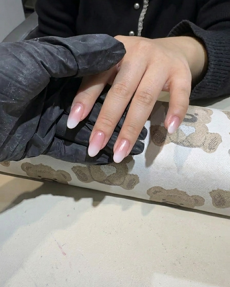 White gel polish being dabbed onto the tip of a nail to form a gradient.