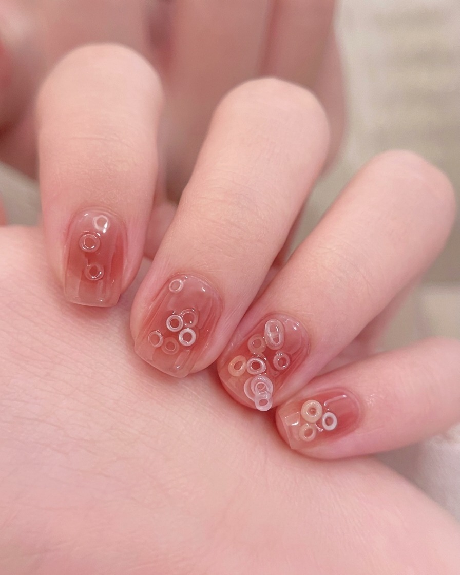 A small brush applying a clear base coat over a clean, natural fingernail.