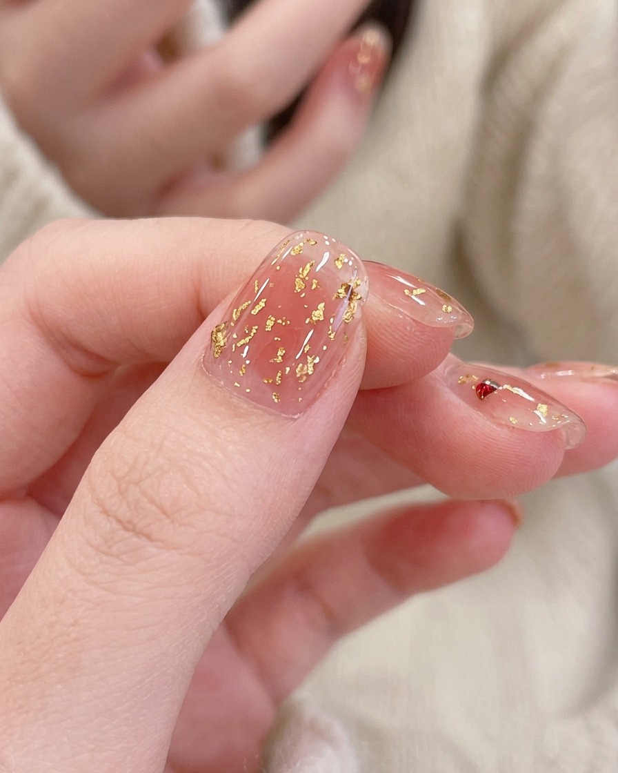 A thin nail art brush painting small, delicate white petals onto a pink cat-eye gel nail.