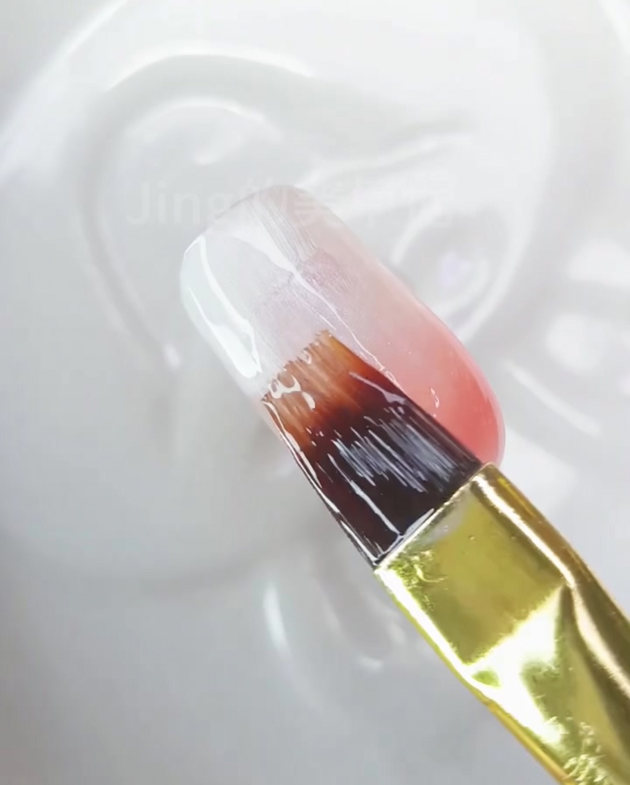 A close-up of a nail showing a smooth, finished ombre blend from white to peach-pink.