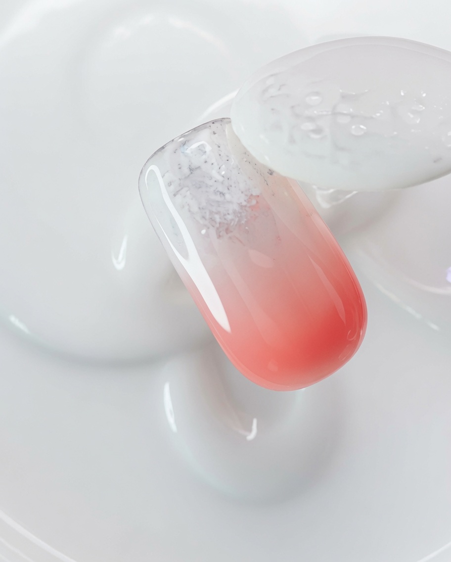 A brush applying clear magnetic cat-eye gel over a nail coated with aurora powder.