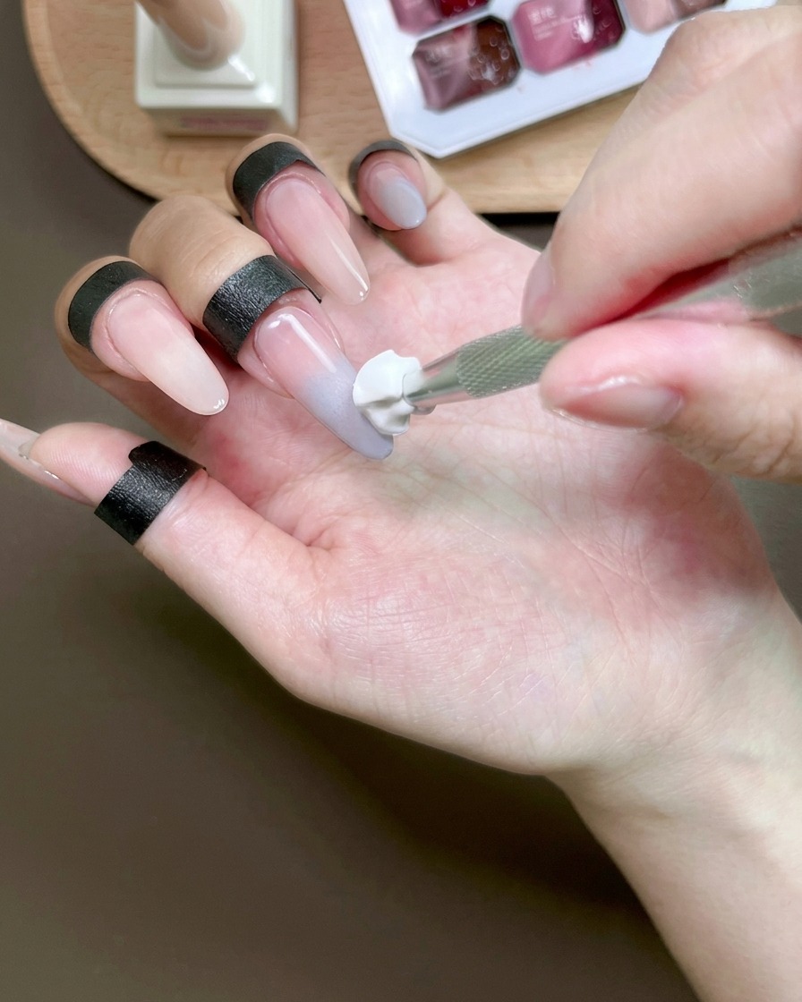 A sponge tool blending blue gel on a fingernail to create an ombre effect.