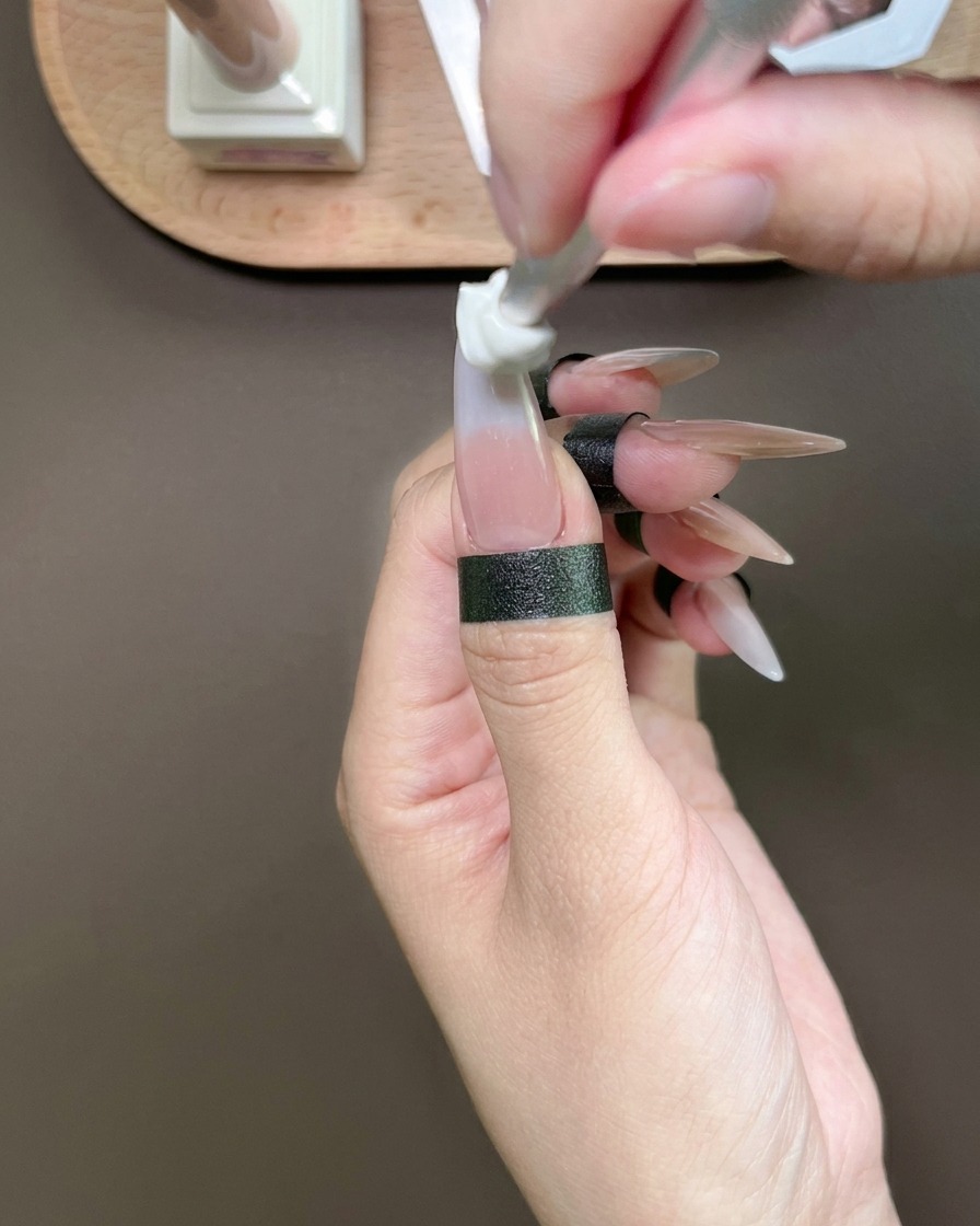 A sponge tool dabbing blue gel onto the tip of a thumb to create a gradient.