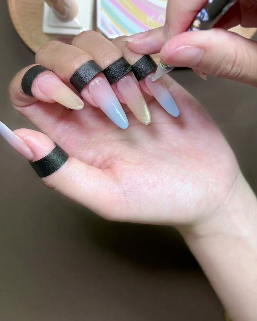 Close-up of a dotting tool applying tiny dots of clear adhesive to a gel-manicured nail.