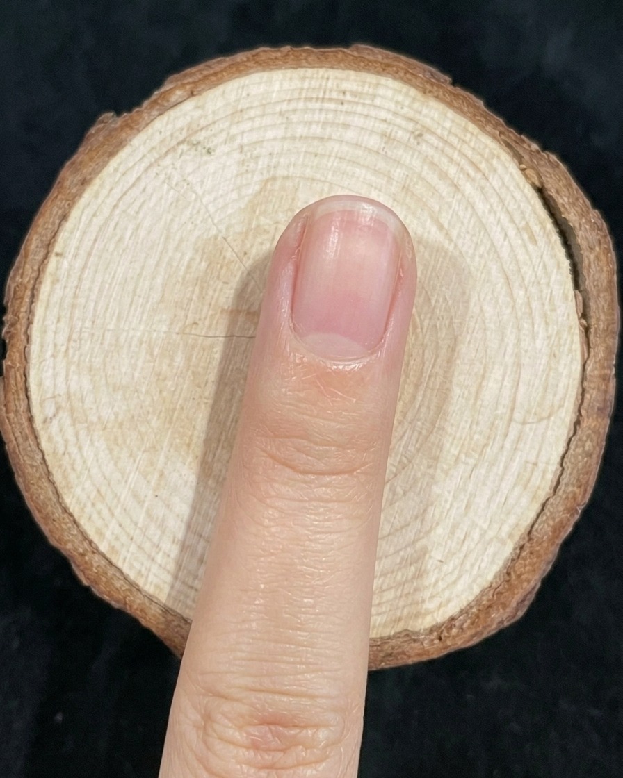A nail brush lightly blending the junction of green and blue polish on a nail.