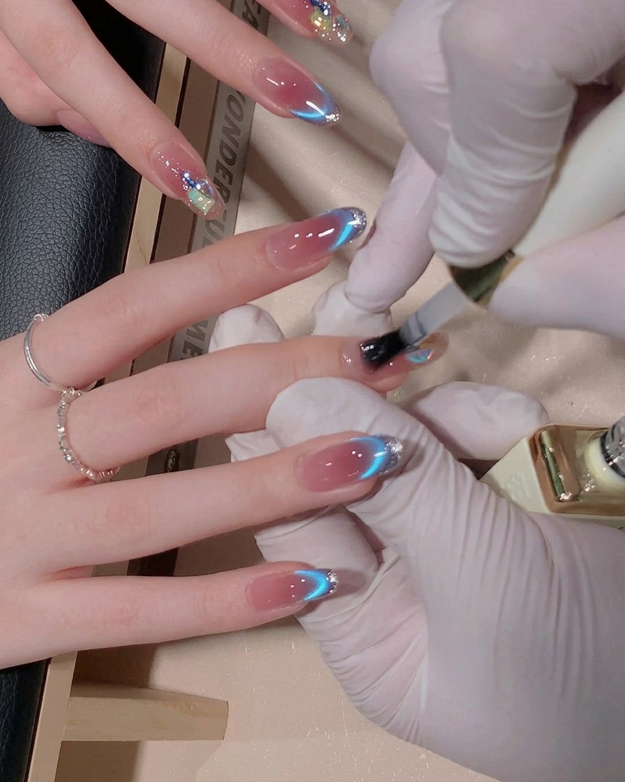 A brush applying a layer of glossy top coat gel over a decorated fingernail, making the surface look wet and shiny.